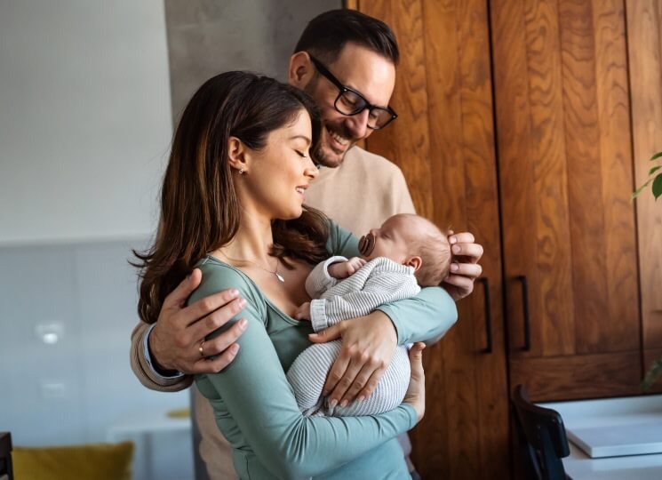 Mother holding baby while father smiles